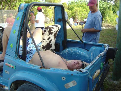 1993 Ford Bronco - A man relaxes in the back of a blue off-road vehicle while another man stands nearby.