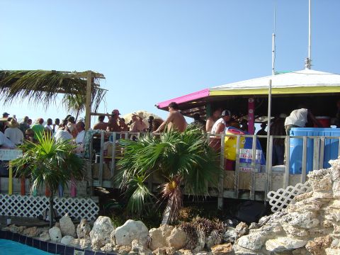1993 Ford Bronco - A lively beach bar scene unfolds under a clear blue sky, with patrons enjoying the atmosphere on a wooden deck.