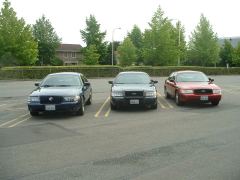 1999 Ford Crown Victoria - Three Ford Crown Victoria police interceptors are parked in a lot, viewed from the front.