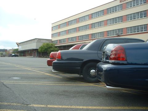 1999 Ford Crown Victoria - Several Ford Crown Victoria police cars are parked in a lot outside a building.