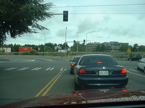 1999 Ford Crown Victoria - A dark blue sedan is stopped at a traffic light, with other vehicles visible in the background.