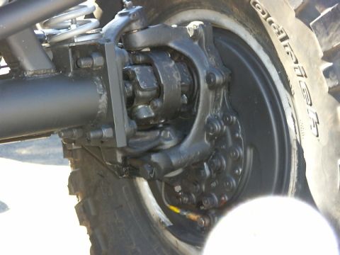 1990 Ford Bronco - A detailed view of the vehicle's suspension system and wheel assembly, with visible mechanical parts and a tire.