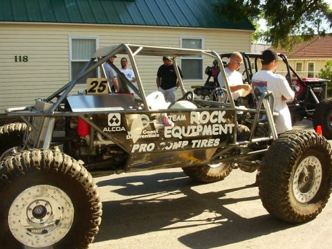 1990 Ford Bronco - Custom off-road buggy with 'Team Rock Equipment' and 'Pro Comp Tires' branding. Another vehicle is parked behind.