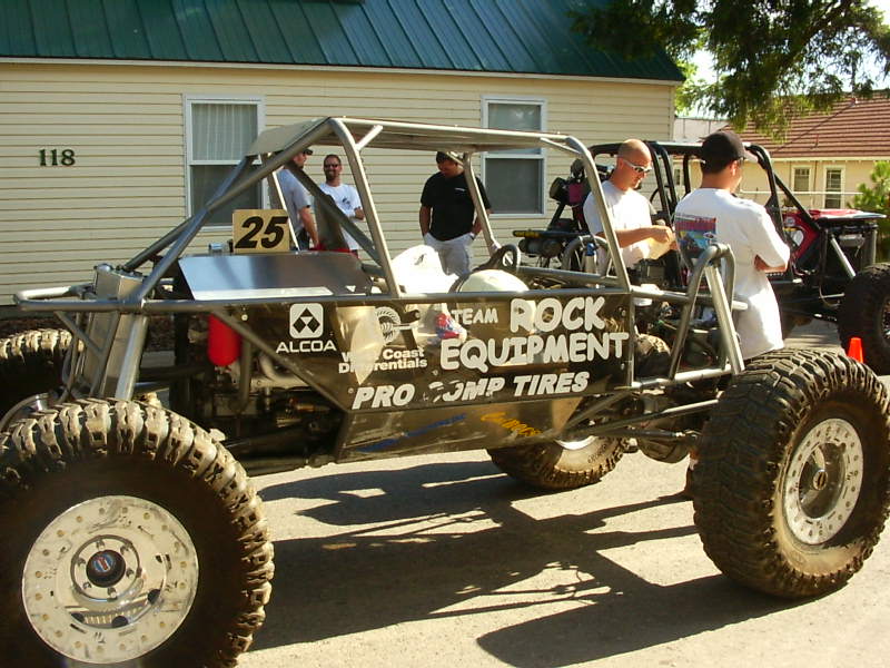 Custom buggy with roll cage, large off-road tires, and 'Team Rock Equipment' graphics. Another buggy is visible behind it
