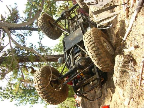 1990 Ford Bronco - This off-road vehicle appears to be stuck on a challenging rocky terrain, with trees visible above.