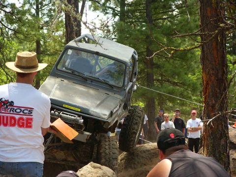 1990 Ford Bronco - An off-road vehicle navigates a challenging rocky course with spectators watching.