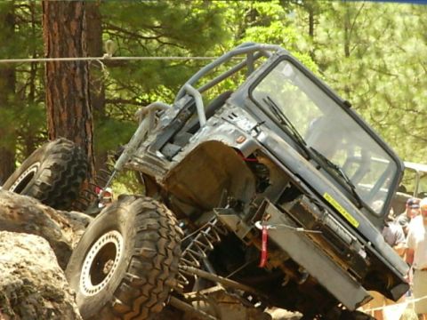 1990 Ford Bronco - Heavily modified off-road vehicle navigating a rocky terrain, with another vehicle in the background.