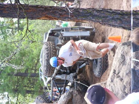 1990 Ford Bronco - A modified off-road vehicle is being maneuvered through a challenging rocky course with spectators watching.