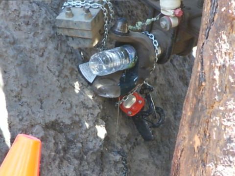 1990 Ford Bronco - A water bottle and chains are attached to a vehicle part, possibly for a repair or modification.