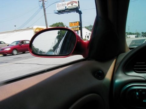 1997 Ford Taurus - Side view of a red 1997 Ford Taurus on the road, captured from inside another car.