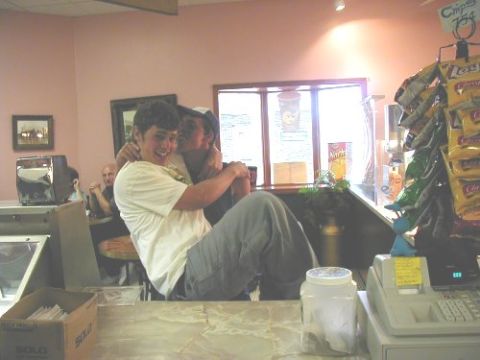 1997 Ford Taurus - Two people embrace behind a counter in a store, with snacks displayed on shelves.