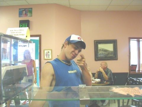 1997 Ford Taurus - A man gestures towards the camera while inside a diner, with other patrons visible in the background.