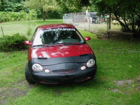 1997 Ford Taurus - A red 1997 Ford Taurus is parked on a lawn, partially covered by a black car bra.