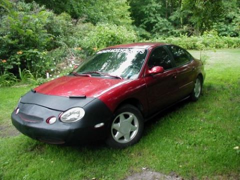 1997 Ford Taurus - Red 1997 Ford Taurus sedan is parked outdoors with a black car bra covering the front end.