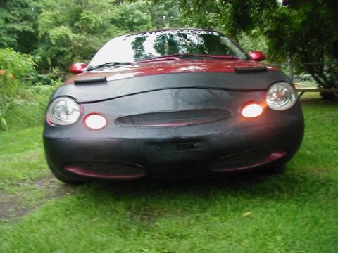 1997 Ford Taurus - A red car is parked outside with a black car bra covering its front end.
