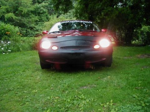 1997 Ford Taurus - A red sedan is parked on a grassy lawn with its headlights illuminated.