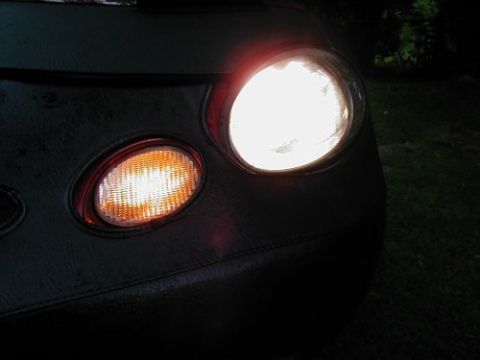 1997 Ford Taurus - Close-up of a car's illuminated headlight and turn signal, partially obscured by a car bra.