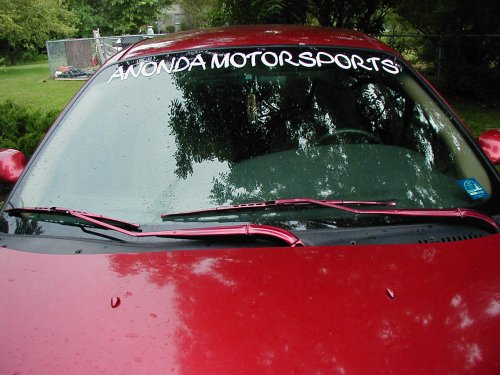 Red car windshield with "ANONDA MOTORSPORTS" banner and "SUPERMOTORS" watermark