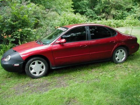 1997 Ford Taurus - Red 1997 Ford Taurus sedan parked on grass with a car bra covering the front bumper.