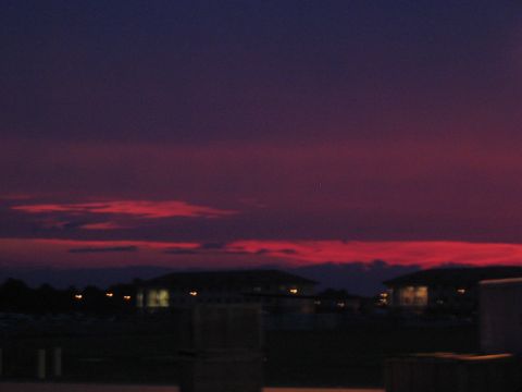 1988 Ford Bronco - A vibrant sunset paints the sky with hues of purple and red above a silhouetted landscape of buildings and distant lights.