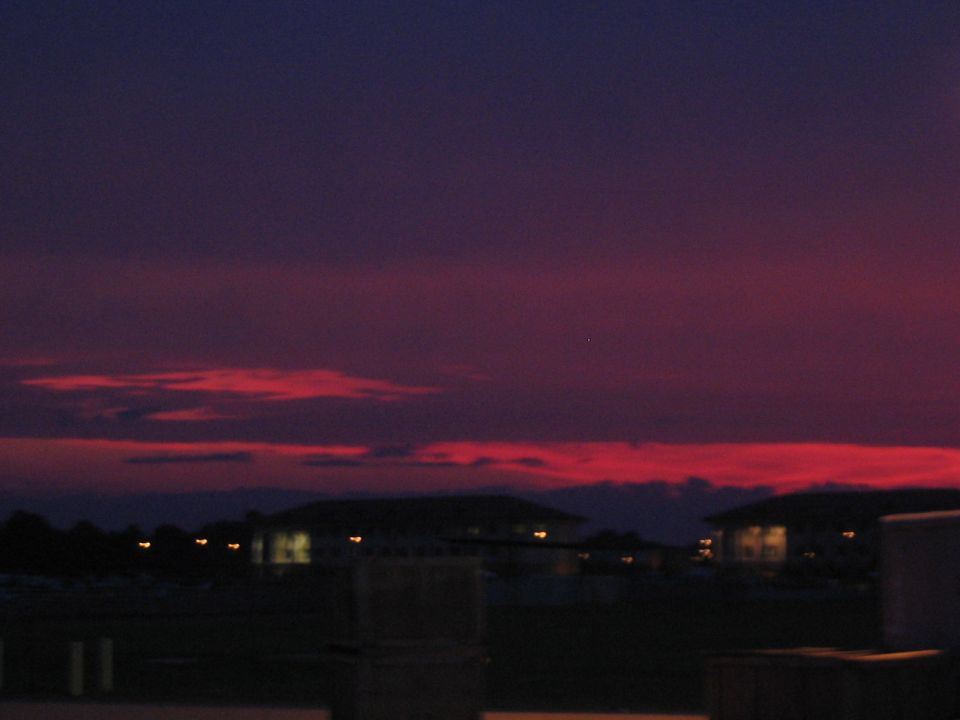 Sunset sky with red clouds over silhouetted buildings and lights