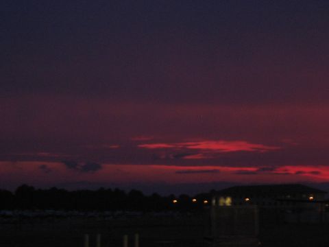 1988 Ford Bronco - A colorful sunset paints the sky over a dark landscape with a building illuminated by lights.