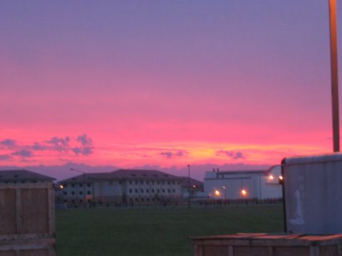 1988 Ford Bronco - A vibrant sunset paints the sky with pink and purple hues over a landscape with buildings and a trailer.