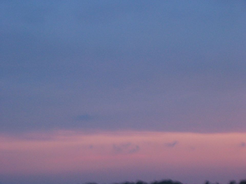 Sky with pink and blue hues above a silhouetted treeline and a SUPERMOTORS watermark
