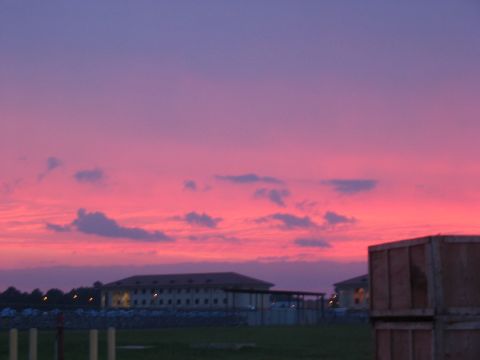 1988 Ford Bronco - A colorful sunset paints the sky above a row of buildings and a large wooden structure.