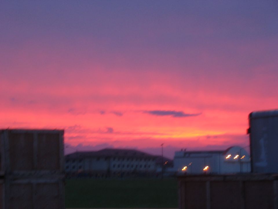 Buildings and containers against a vibrant pink and purple sunset sky