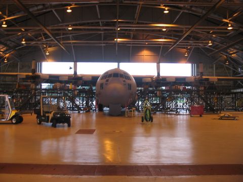 1988 Ford Bronco - Airplane fuselage is parked inside a large hangar, with several utility vehicles visible around it.