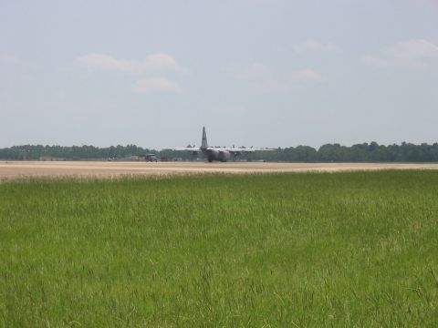 1988 Ford Bronco - A large military cargo plane is on a runway with trees and a cloudy sky in the background.