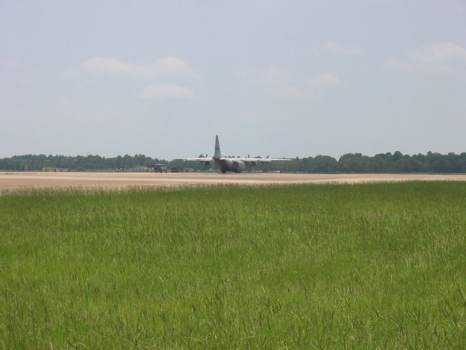 military cargo plane on runway with grass in foreground