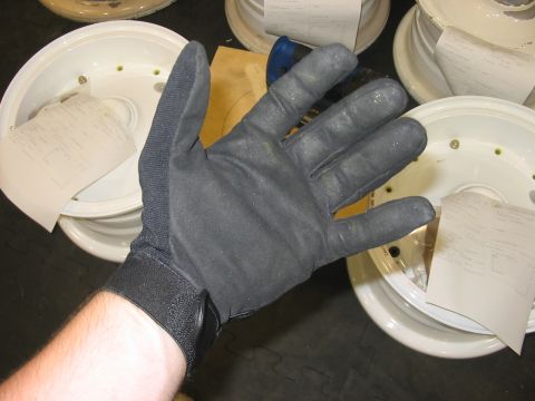 1988 Ford Bronco - A gloved hand is held up over a stack of white car wheels, some with papers tucked inside.