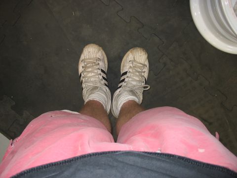 1988 Ford Bronco - A person's feet and legs are shown wearing white sneakers and pink shorts on a dark floor with a watermark.