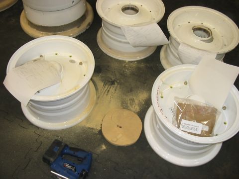 1988 Ford Bronco - White rims are prepared for work, with tools and supplies nearby on the floor.