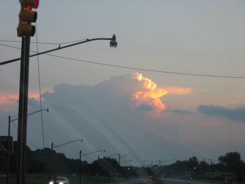 1988 Ford Bronco - A dramatic cloud formation is illuminated by sunset light over a road with traffic lights.