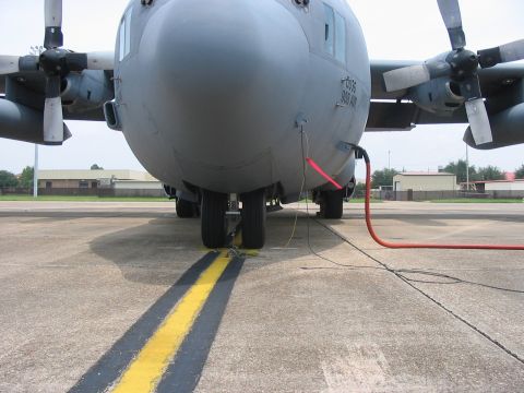 1988 Ford Bronco - A C-130 Hercules aircraft is seen from the front on a tarmac, connected to a refueling hose.