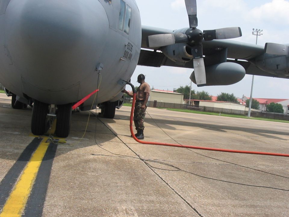 Ground crew fueling a large gray military cargo plane on an airfield