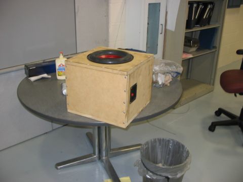 1988 Ford Bronco - A wooden speaker box sits on a round table, next to a bottle of glue and other items.