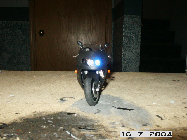 Black sport motorcycle with headlights on, parked indoors