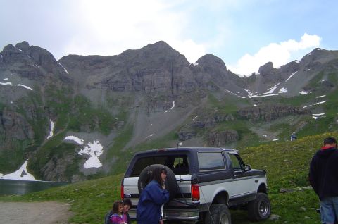 1993 Ford Bronco - A 1993 Ford Bronco is parked on a scenic mountain overlook, with people gathered around.
