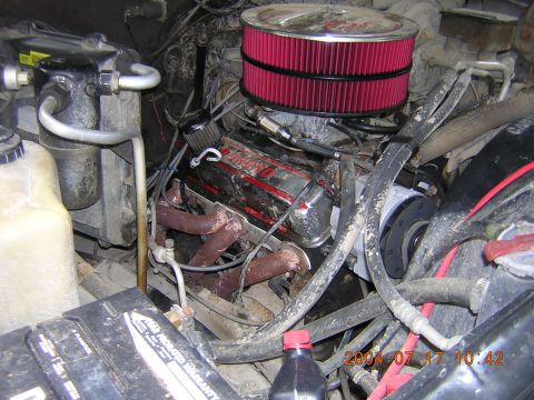 1984 Chevrolet Blazer - The engine bay of a vehicle, a prominent red air filter and chrome valve covers, with visible hoses and wiring.