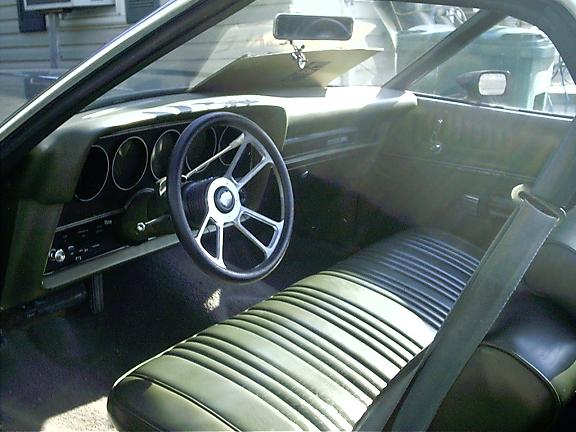 Interior of a vintage muscle car with green upholstery and round gauges