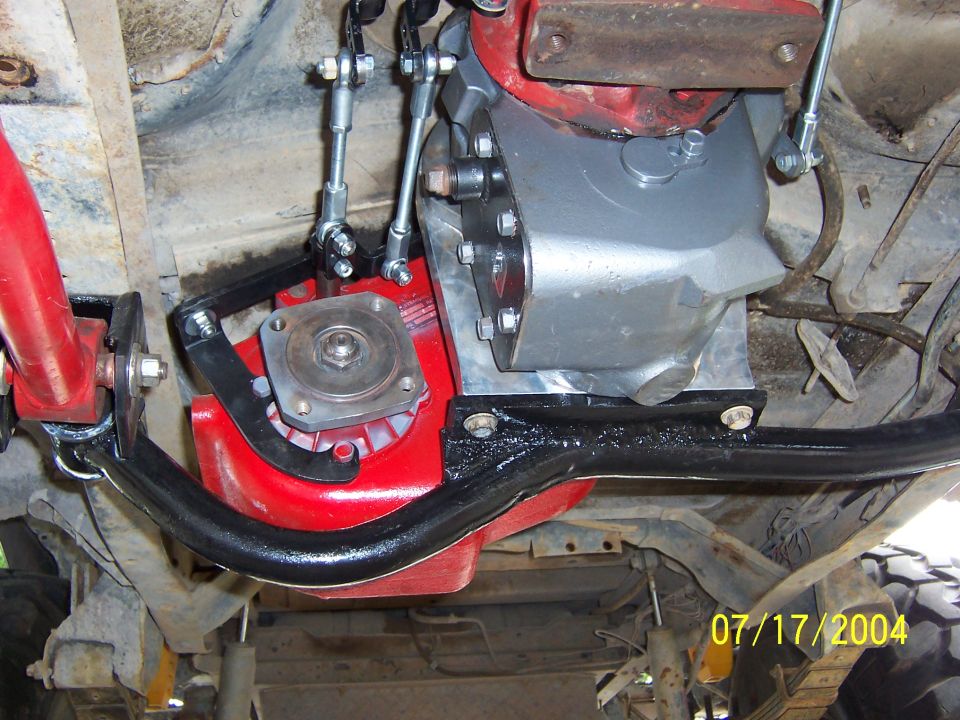 Underside view of red transfer case with shift linkage and black crossmember on a 1978 Ford Bronco