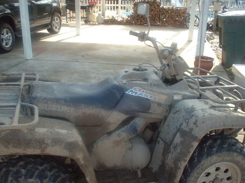 1976 Ford F-150 - This dirty ATV has 'Quad Master' written on its side. A dark SUV is visible in the background.