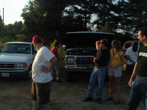 1988 Ford Bronco - A group of people stand around a 1977 Ford truck with its hood open, parked next to another vehicle.