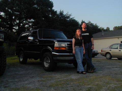 1988 Ford Bronco - A black SUV is parked outside with two people standing next to it. A watermark for SUPERMOTORS is visible at the bottom right.