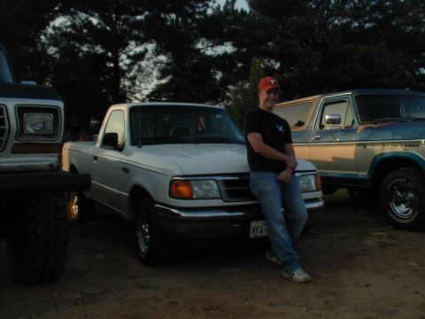 1988 Ford Bronco - A man poses with his Ford Ranger pickup truck, with other classic Ford vehicles in the background.
