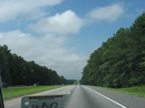 1988 Ford Bronco - Driving down a highway surrounded by trees under a partly cloudy sky.